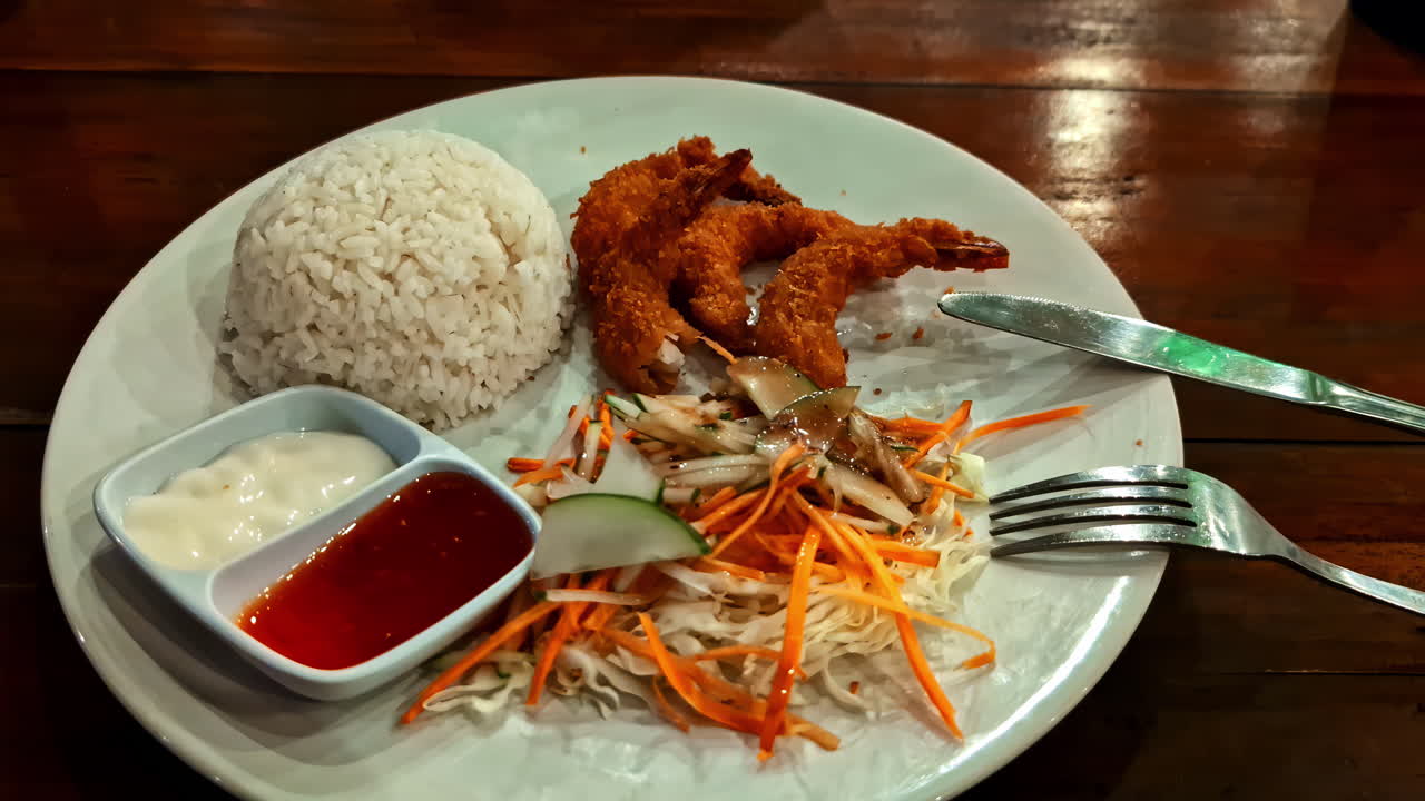 A delicious dish with breaded prawns with rice, vegetables and sauces