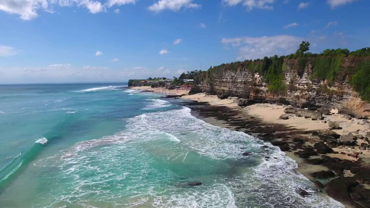 Vista aerea in avanti delle scogliere e della spiaggia di Uluwatu, veduta estiva di una spiaggia tropicale indonesiana con maestosa scogliera rocciosa, filmato a Bali.