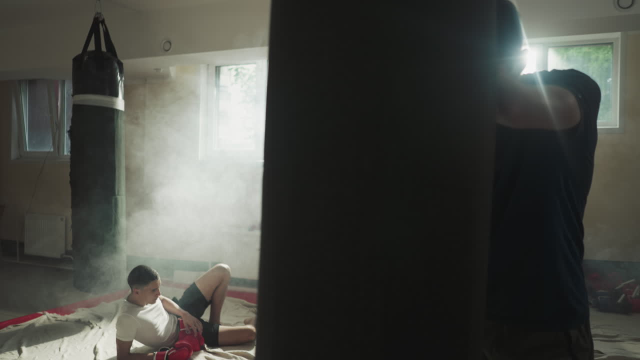 피곤한 남성 운동선수 그룹은 힘든 권투 세션 후에 휴식을 취합니다. 신체 활동으로 인한 피로. 전투 스포츠에 참여하고 스포츠 클럽에서 힘을 향상시니다.