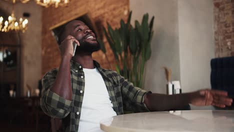 black person laughing while talking on the phone in a cafe, rest