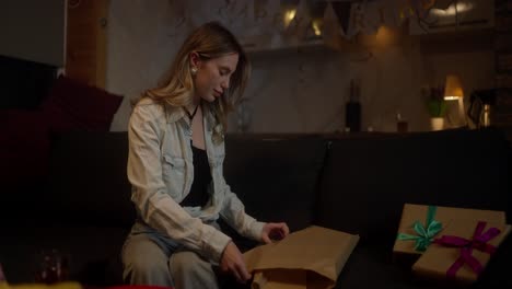 mujer abriendo un regalo de cumpleaños en un sofá