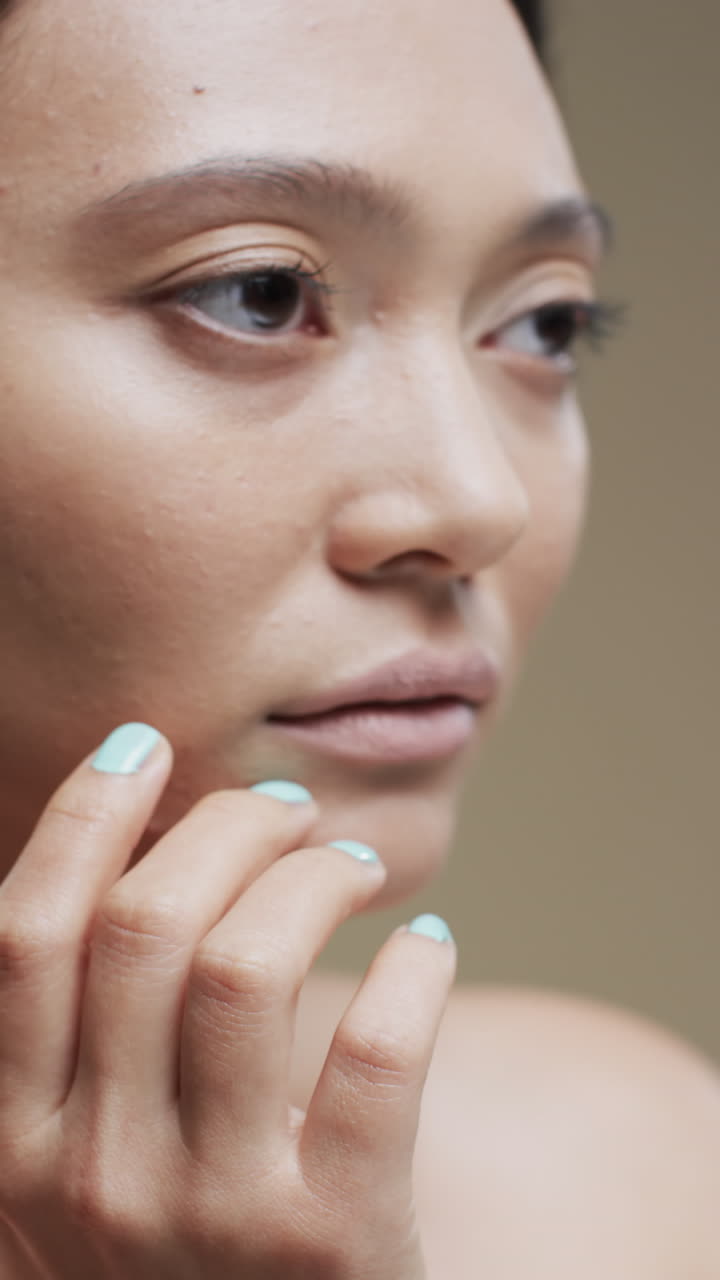 Vertical video of asian woman with dark hair on beige background, slow motion