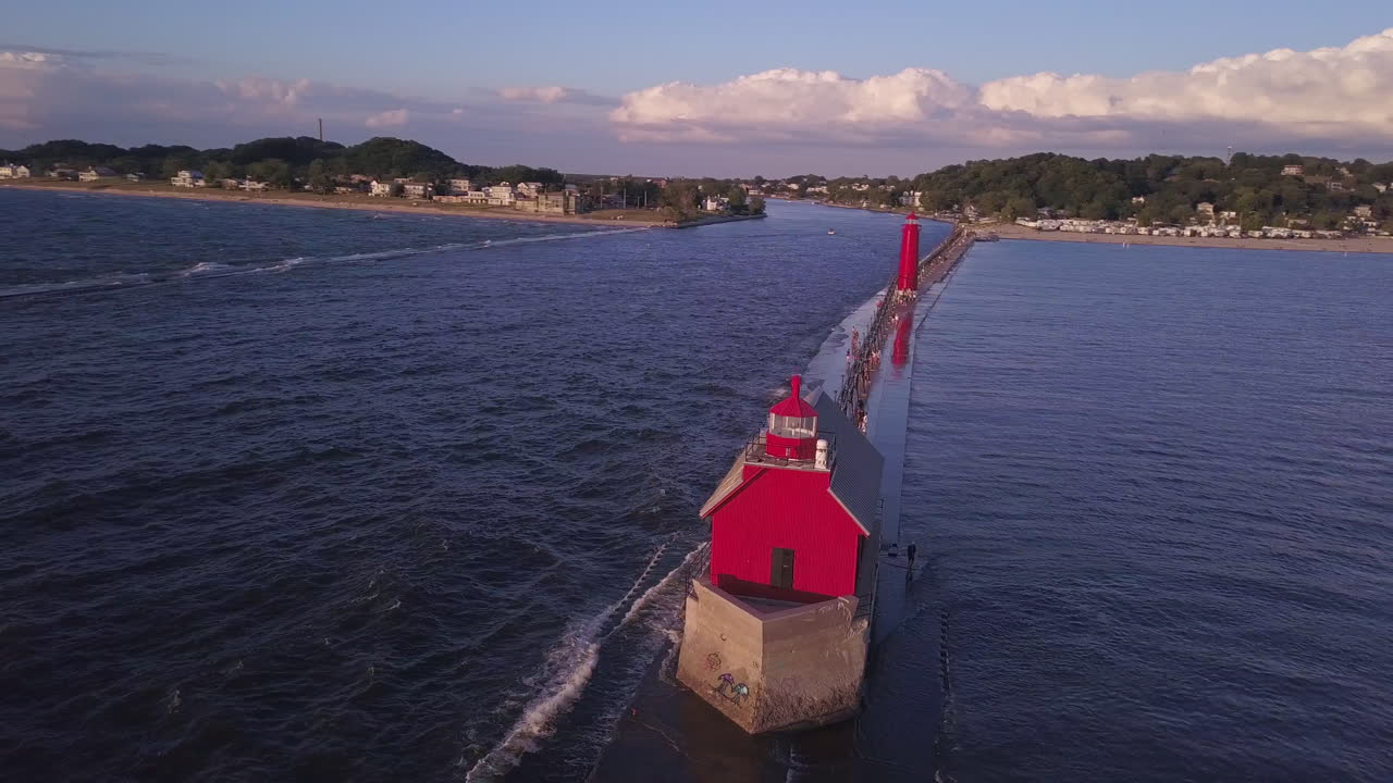 Aerial parallax of red Grand Haven Lighthouse on pier by wavy water