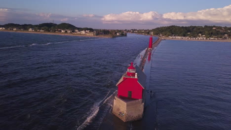 aerial parallax of red grand haven lighthouse on pier by wavy water