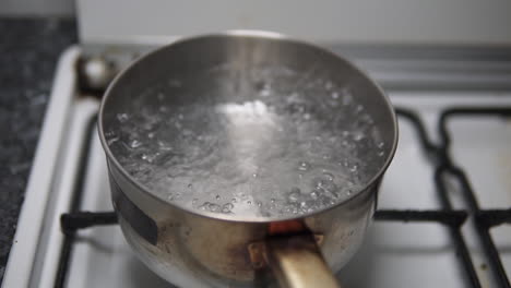 water boiling in a rusty old stainless steel pot on the fire stove