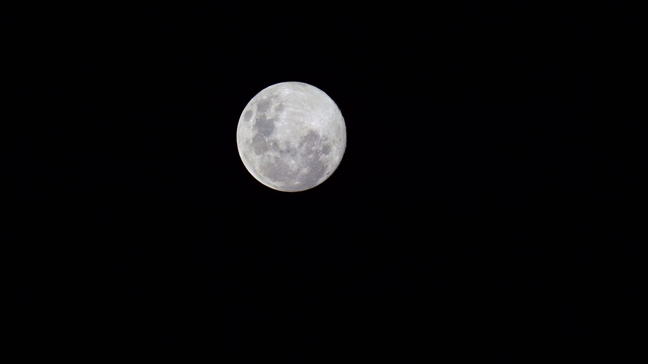 Uma visão detalhada da lua cheia à noite contra a extensão escura do espaço, capturada em uma filmagem time-lapse do Hemisfério Sul
