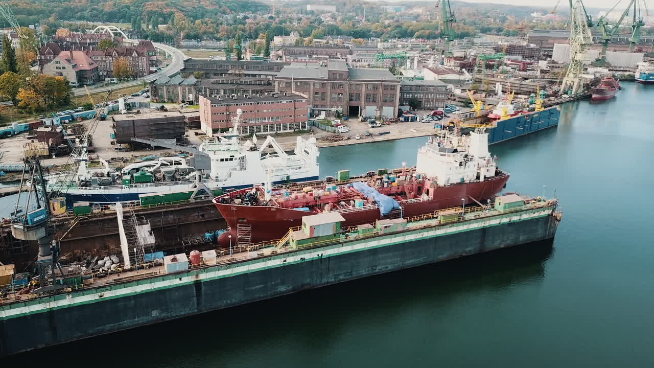 조선소 부두에서 크레인과 화물선 주위를 비행하는 드론