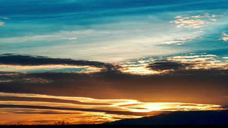 waves of clouds cross the sky in the vibrantly colorful sunset time lapse