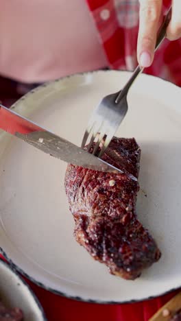 woman cutting steak with knife and fork