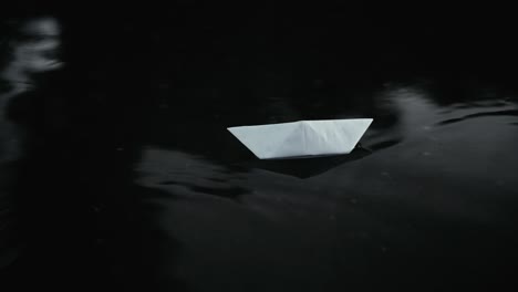 Close-up-a-white-paper-boat-floats-through-a-deep-puddle-after-rain-on-the-street