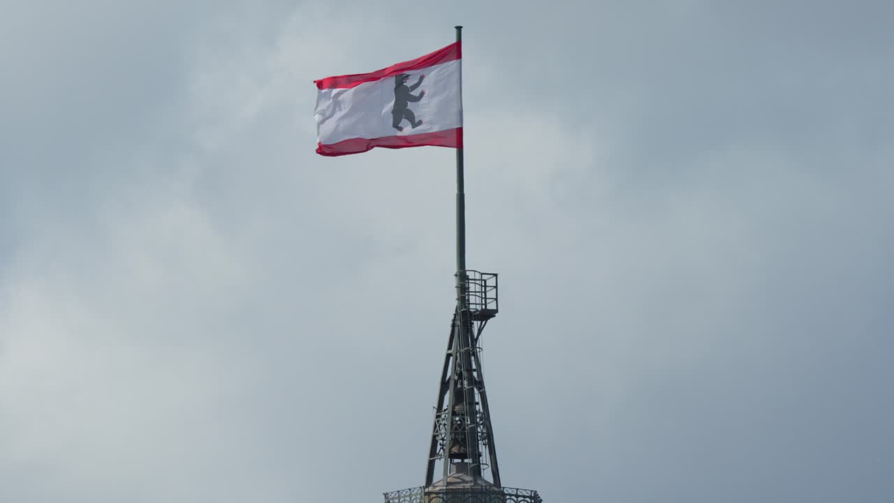 Berlin city flag waves atop historic tower against cloudy sky, static camera, natural daylight