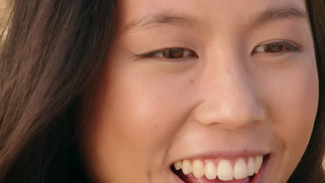 Primer-Plano-Retrato-De-Una-Feliz-Mujer-Asiática-Sonriendo-Disfrutando-De-Un-Día-Soleado-Relajándose-En-Las-Vacaciones-De-Verano-Con-El-Viento-Soplando-El-Pelo