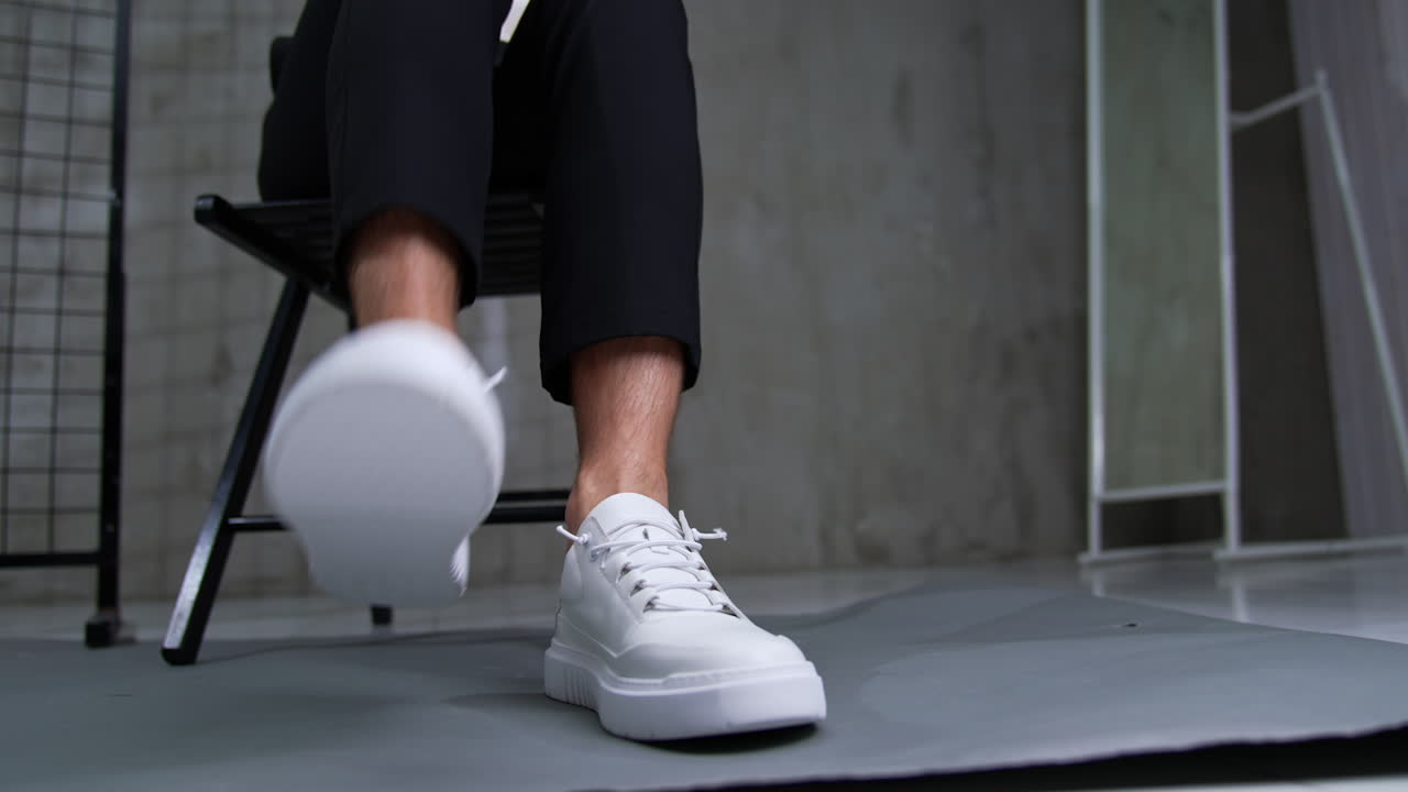 Man Sitting in Chair with White Sneakers