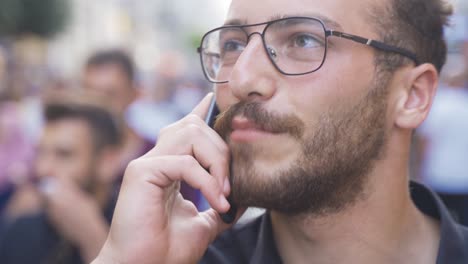 ein junger mann, der am telefon spricht und in der menge lacht.