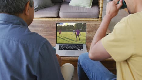 video de varios amigos hombres sentados en el sofá y viendo fútbol en la computadora portátil en casa