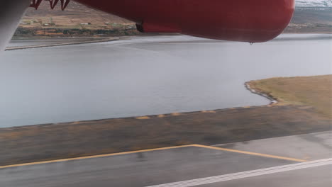 Side-POV-shot-of-small-prop-plane-landing-on-Akureyri,-Iceland-airstrip