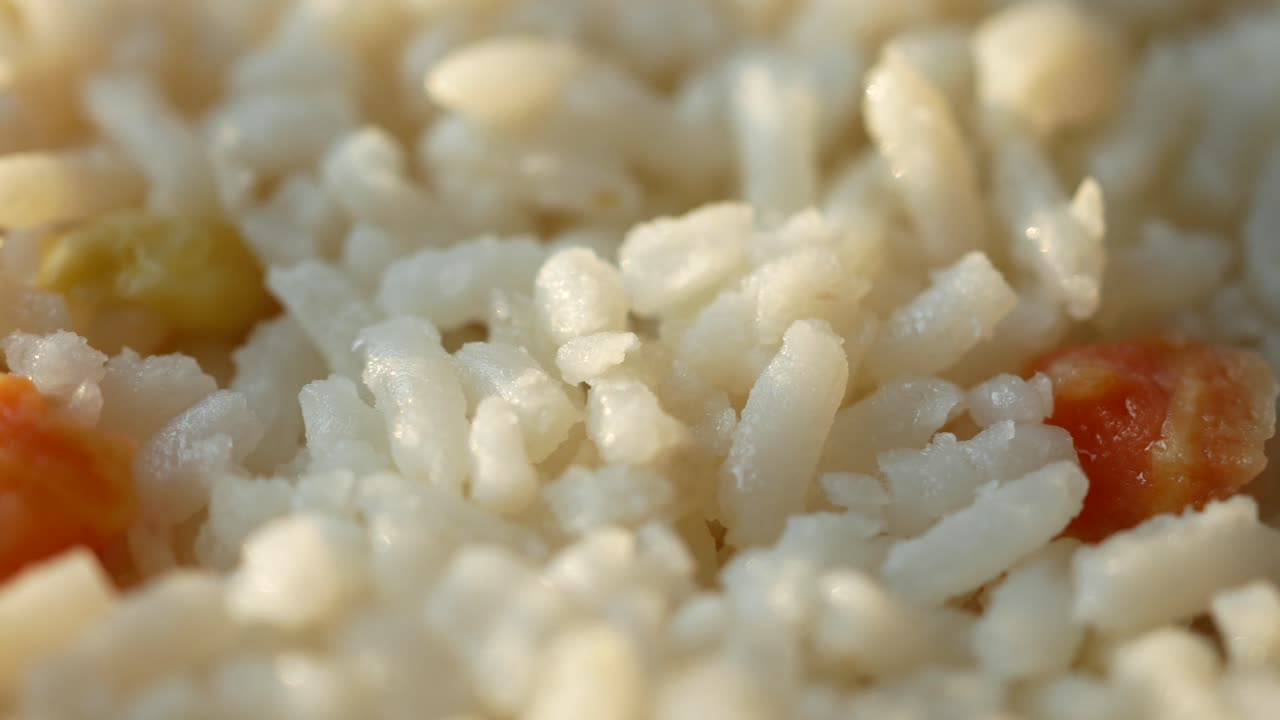 cerca de un plato de arroz con guisantes amarillos y zanahorias