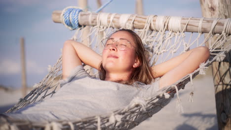 mujer joven relajándose en una hamaca en la playa, sonriendo