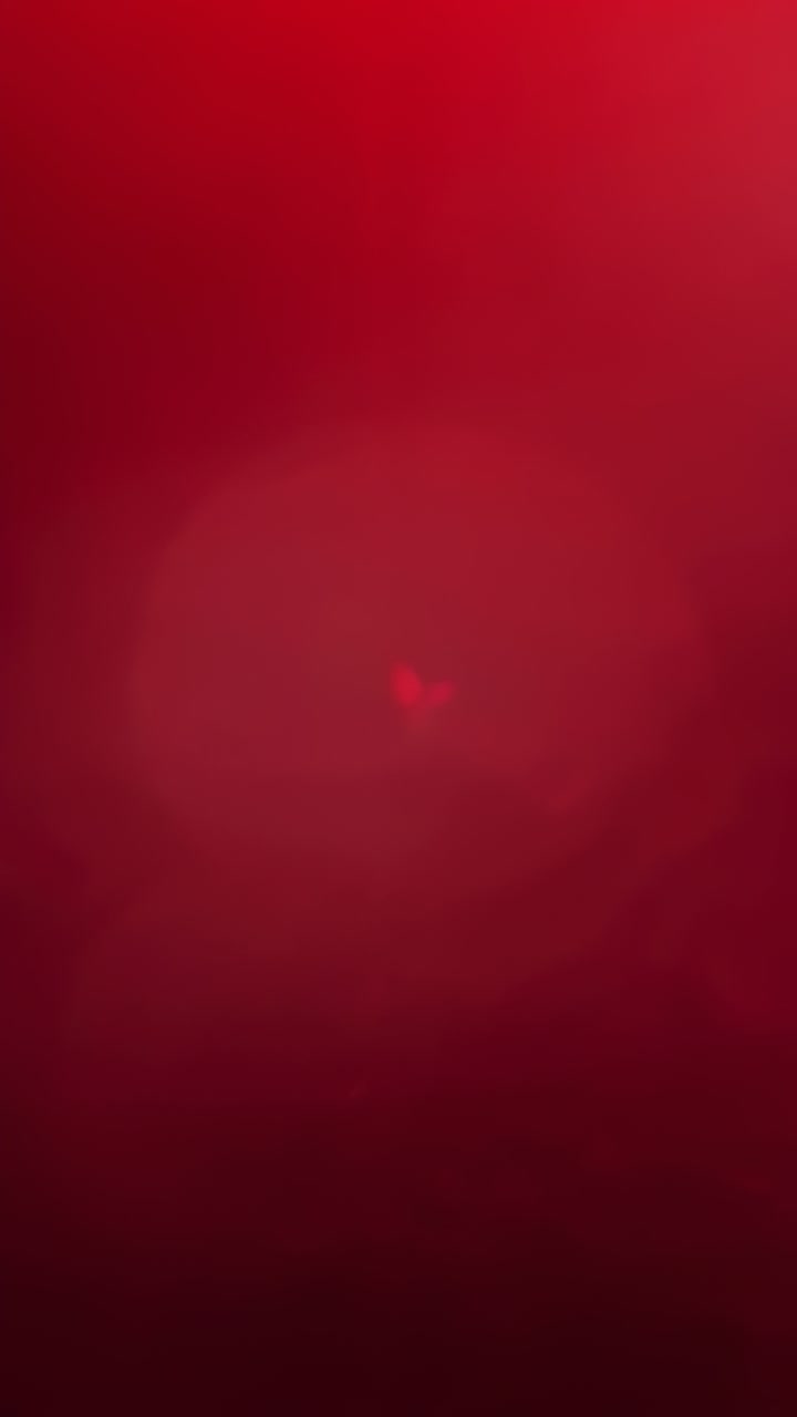 Video verticale: alone lucente che reagisce allo spostamento della luce in una luce rossa, con messa a fuoco e deriva speculari