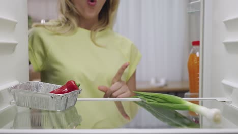 woman checking food in refrigerator