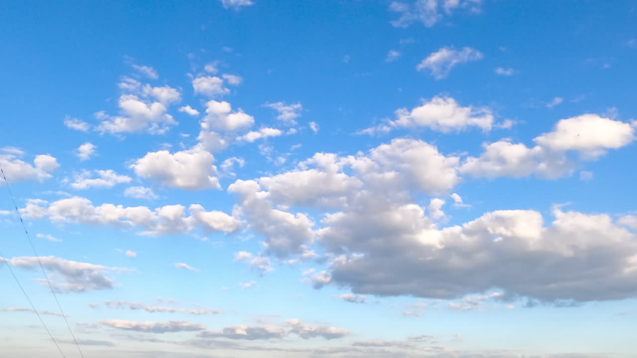 Big and separate little clouds float in the amazing blue sky. Timelapse of light fluffy clouds moving in the horizon.