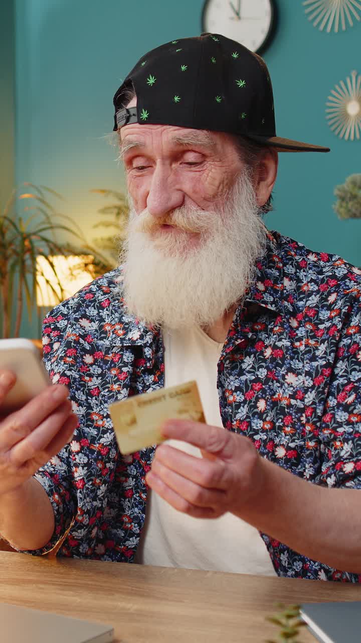 Happy senior man using bank credit card and laptop for online shopping payments at home office