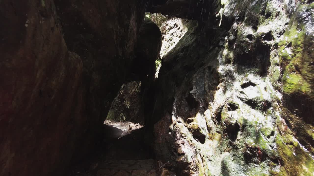 caminando a través de un estrecho túnel de roca con cascada, pov dolly