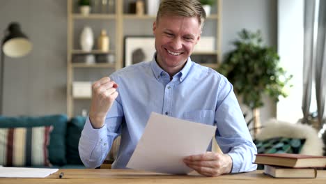 hombre de negocios emocionado después de leer los papeles del contrato en el trabajo