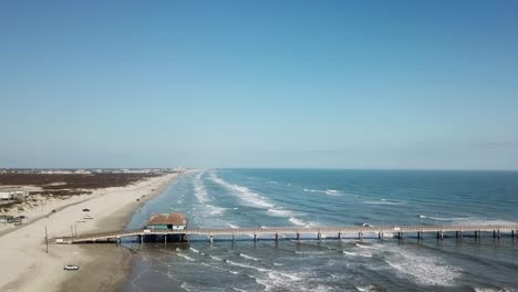 high angle aerial view of bob hall pier, beach and surf at nueces county coastal park on north padre island, texas