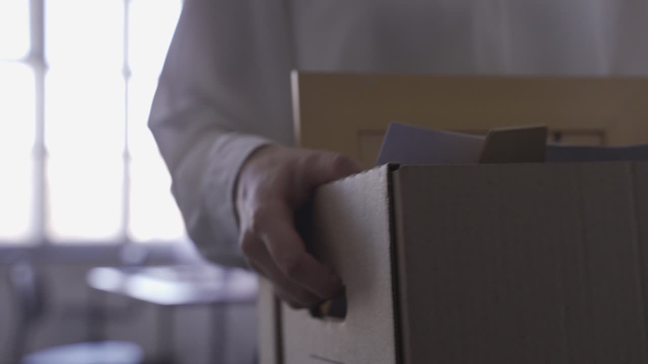 Close-up of woman's hands carrying her things in a box. She is quitting her job.