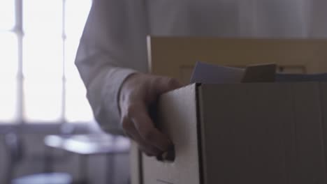 Close-up of woman&#039;s hands carrying her things in a box. She is quitting her job.