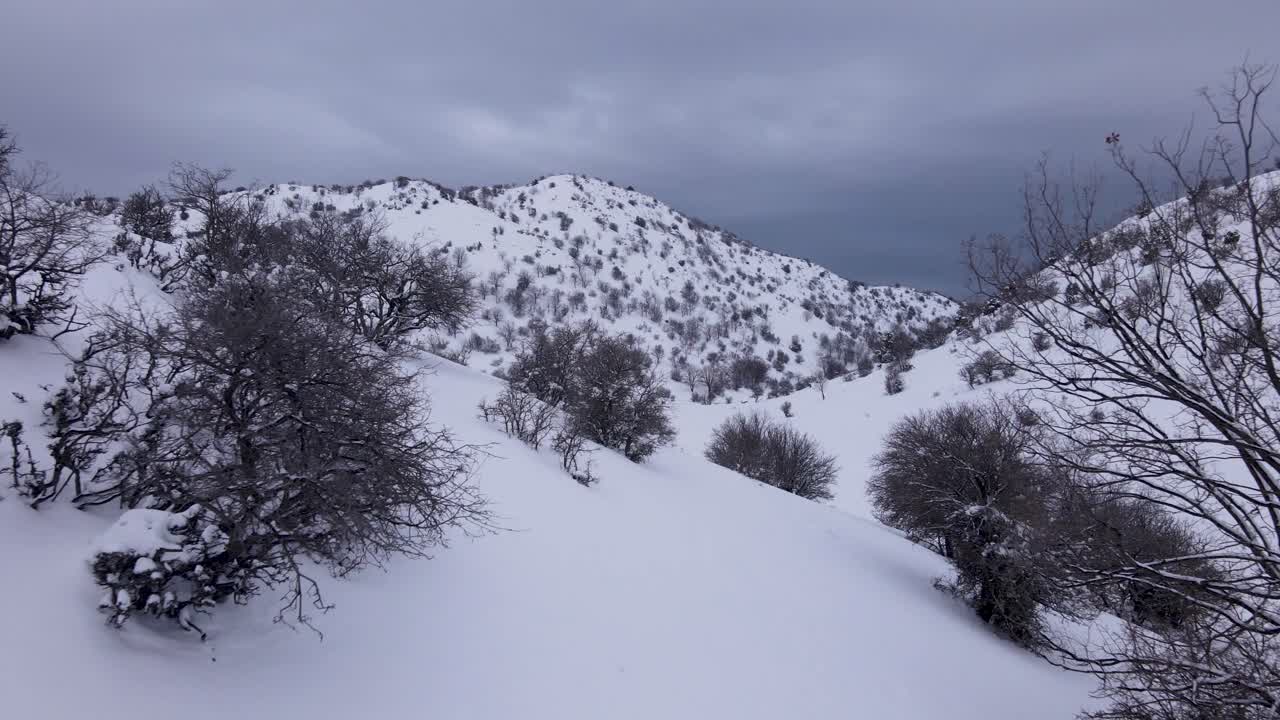 작은 언덕 위를 날아다니며 눈 인 풍경을 통해 트레킹하는 사람들을 드러니다.