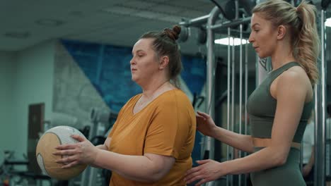 caucasian woman with overweight doing training with fitness instructor at the gym.