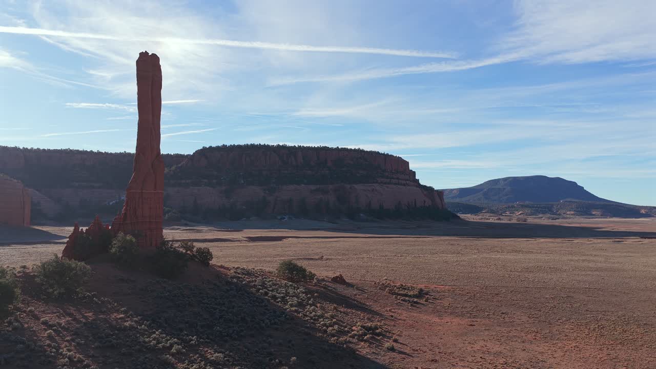 Catturando la bellezza naturale dell'alto deserto, questa ripresa con drone mostra un pinnacolo di roccia rossa con un intenso flare dell'obiettivo, mettendo in risalto la vastità epica di un canyon profondo e la maestosità selvaggia dell'area.