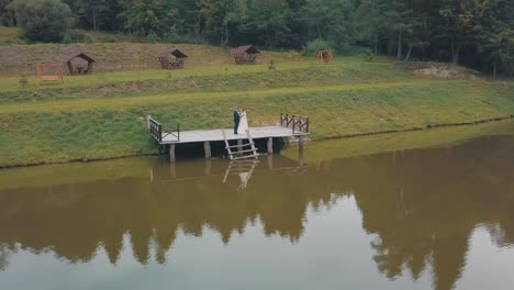 Groom-with-bride-near-lake-in-the-park.-Wedding-couple.-Aerial-shot