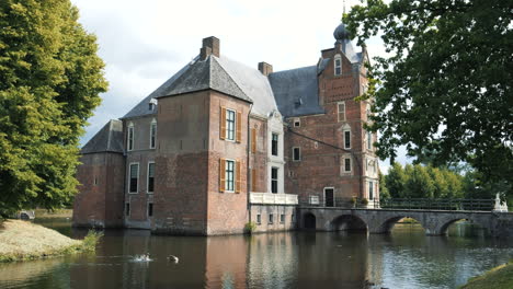 Cannenburch-Castle,-The-Netherlands:-side-view-of-the-beautiful-castle-and-where-you-can-see-the-moat-and-the-bridge-that-crosses-it
