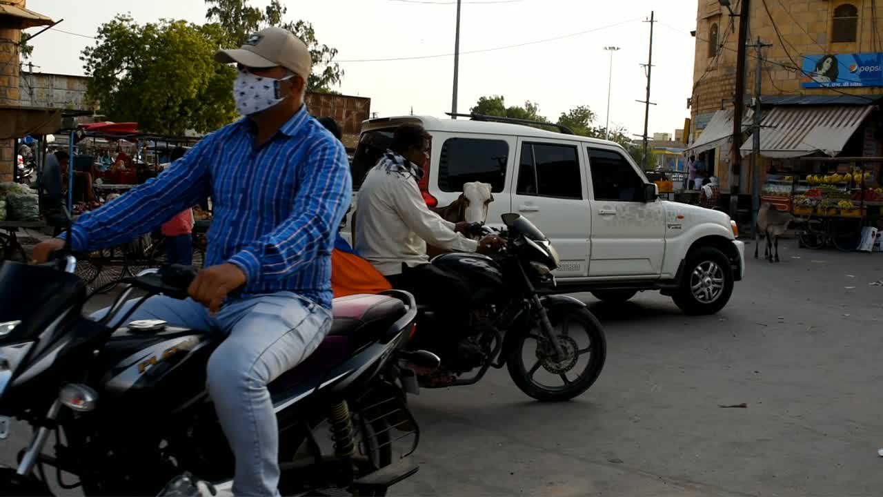 stray cow standing in the middle of the market blocks road, people having difficulty passing