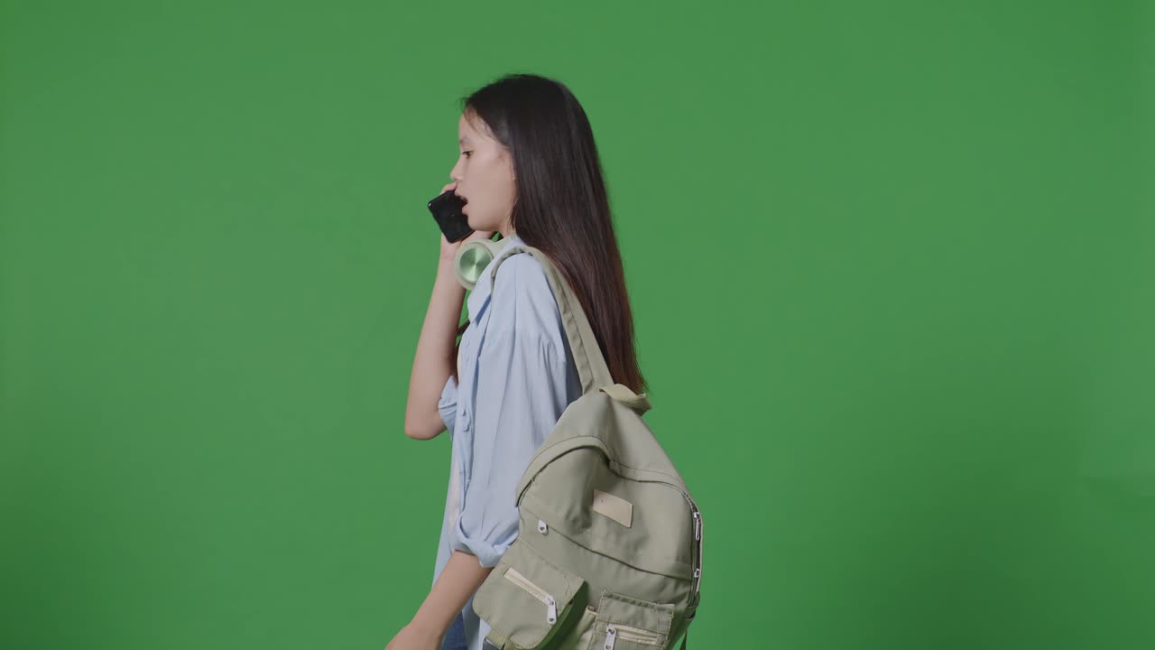 녹색 화면 배경 스튜디오에서 는 동안 스마트폰으로 이야기하는 배을 가진 아시아 십대 소녀 학생의 측면 시각