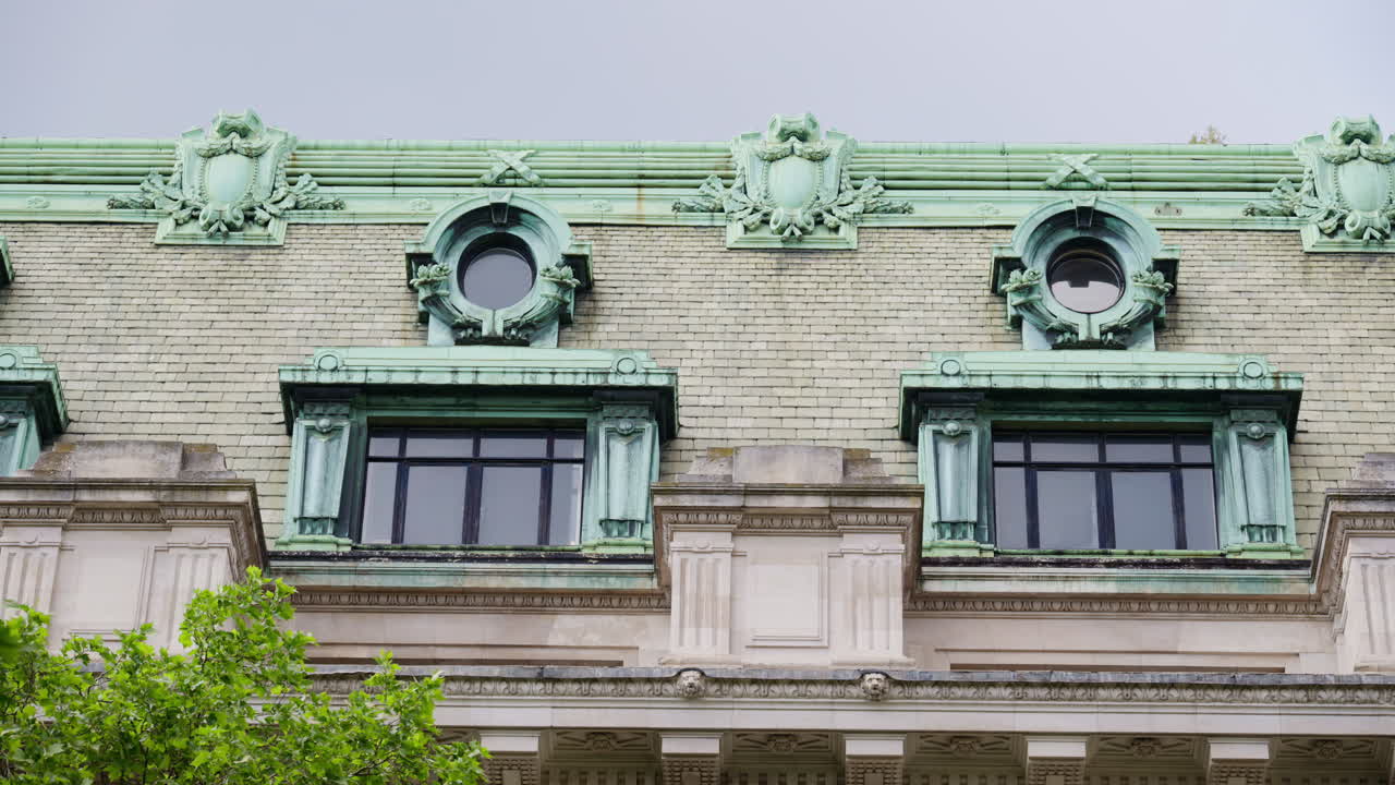 Close up of a historic building with an aged green copper roof and ornate round windows in central London, England