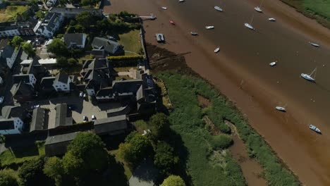 Low-tide-river-aerial-with-pleasure-boats-moored,-pan-down-shot-to-a-top-down-view-of-the-coastline