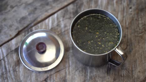 Fresh-brewed-guayusa-tea-in-metal-cup-on-wooden-table