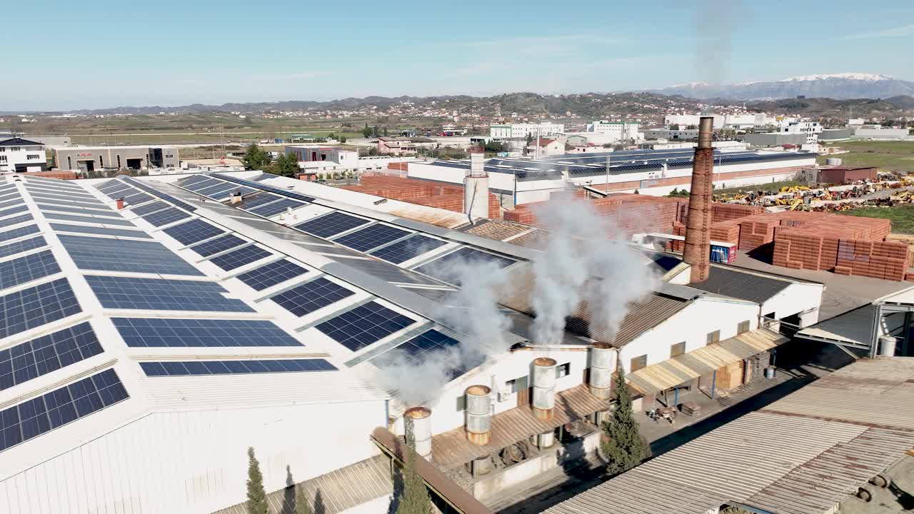 Aerial shot of factory rooftop with chimneys emitting smoke and ...