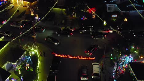 christmas winter wonderland over valencia neighborhood at night with traffic of cars, aerial rising view