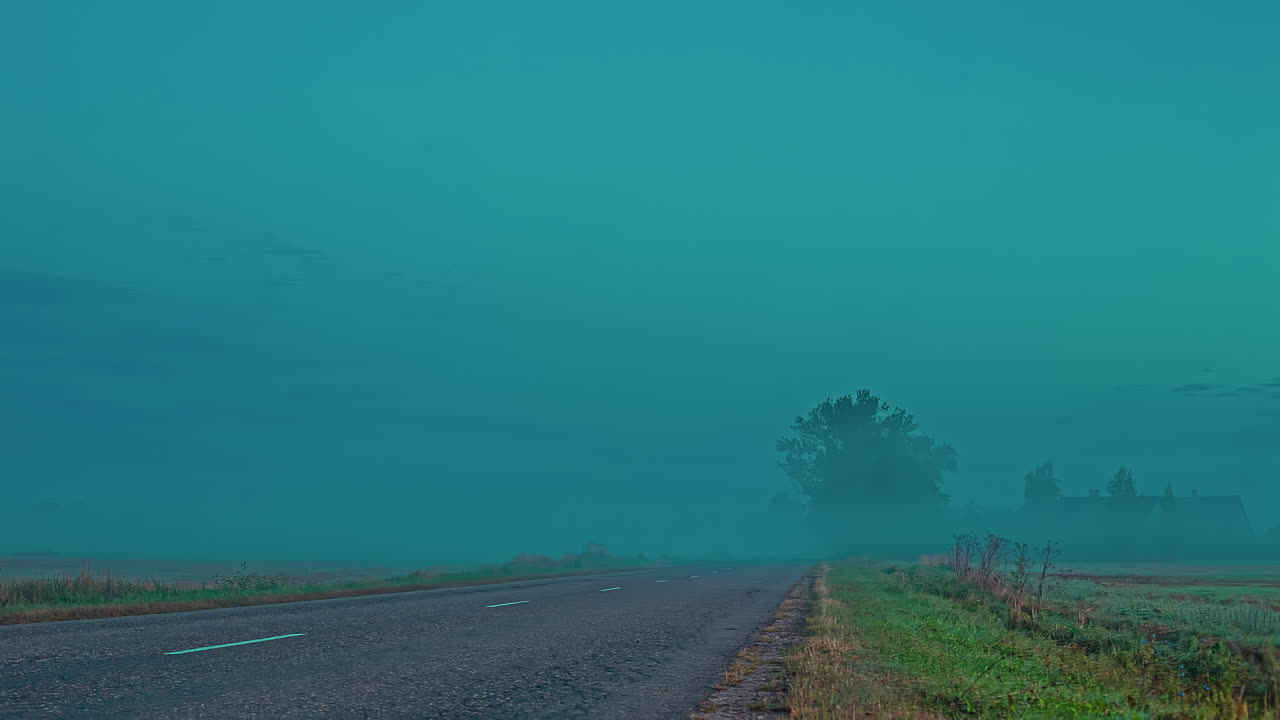 짙은 안개가 끼고 몇 대의 차량이 지나가는 아스팔트 도로의 시간 경과