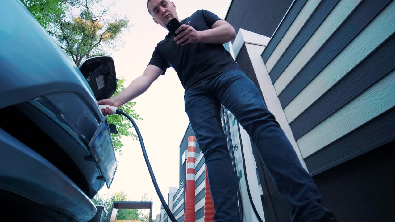 proceso de reabastecimiento de combustible de un automóvil eléctrico. un disparo debajo de la escotilla donde se carga el automóvil ecológico eléctrico. la escotella de carga del automóvil eléctrico se abre automáticamente. una mano masculina inserta un automóvil erecto