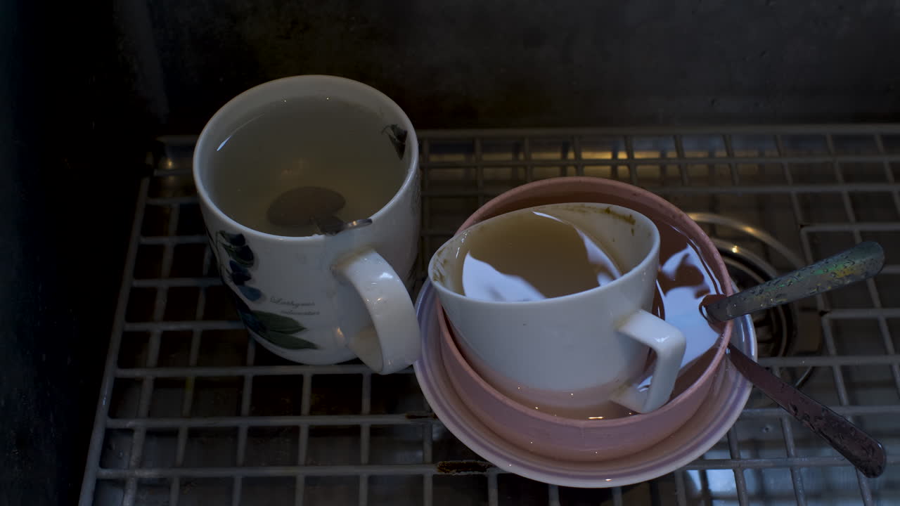 Drops fell from the tap into dirty dishes in the sink