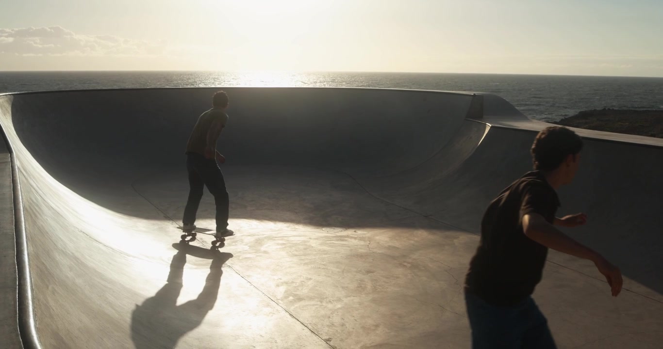 Young Men Skateboarding in Slow Motion at a Coastal Skatepark During Sunset