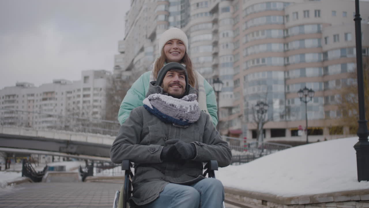 휠체어를 탄 장애인 친구를 데리고 시내를 산책하며 함께 이야기를 나누는 행복한 백인 여성