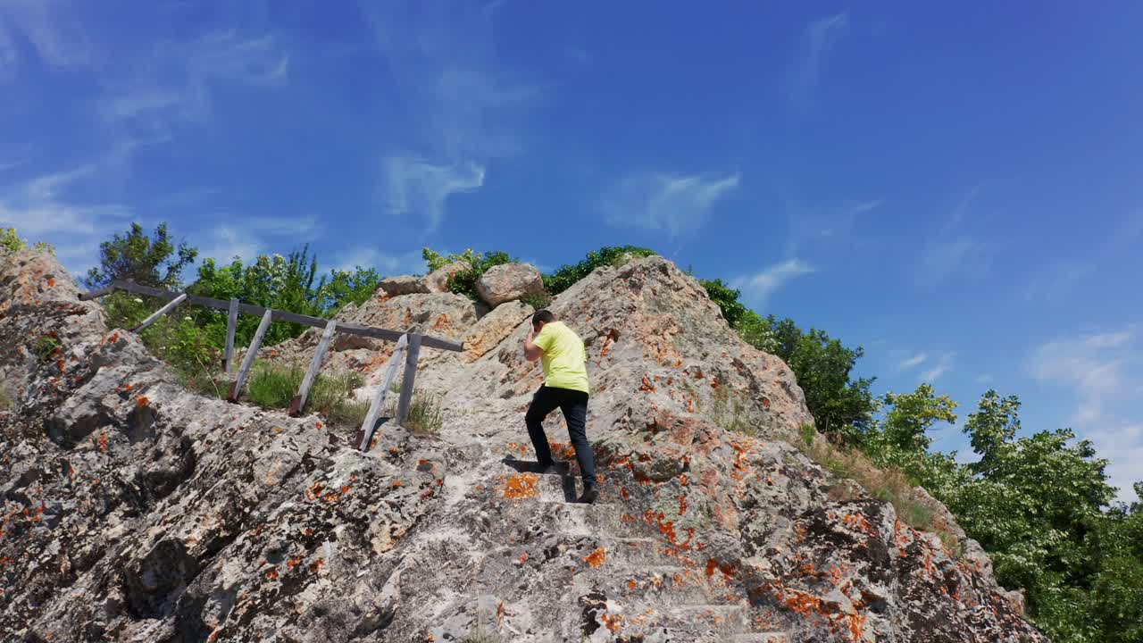 retrato de un hombre escalando escalones de piedra tallados en formaciones rocosas de las piedras sordas en la montaña rodope bulgaria