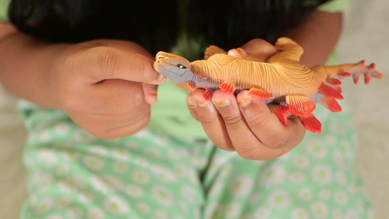 Child's Hands Playing with a Colorful Dinosaur Toy